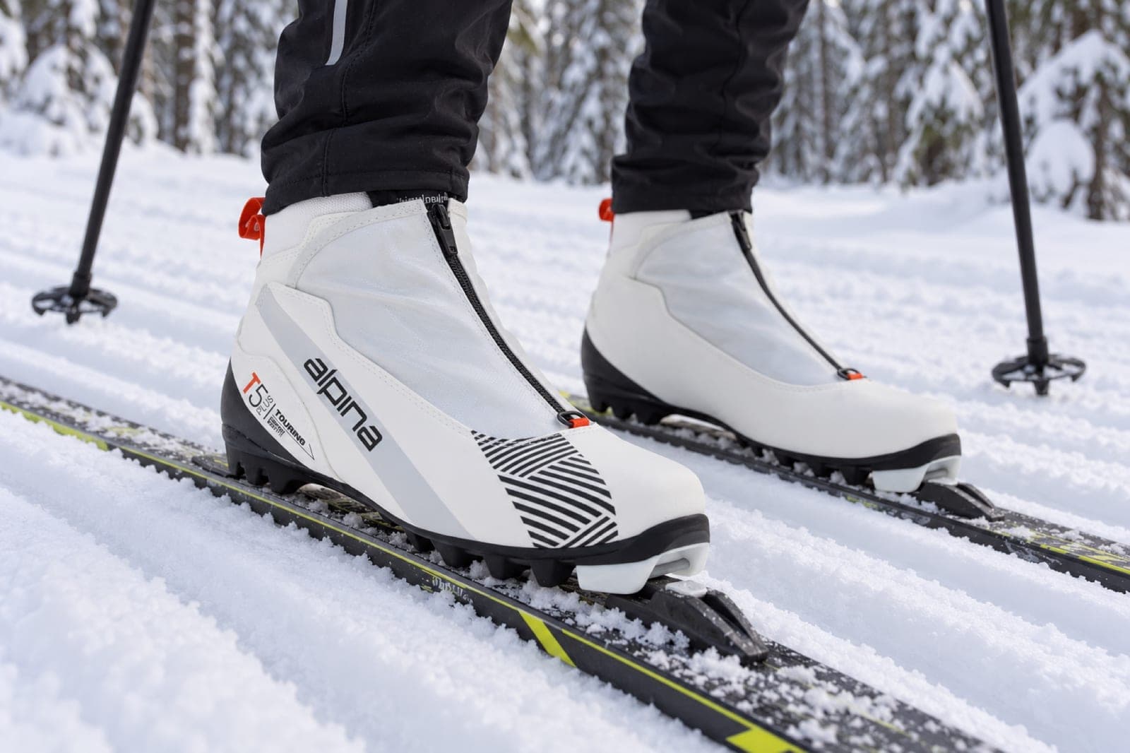 Illustrasjonsbilde laget med KI: et par Alpina T5 Plus Eve i bindingene på et par ski, sett skrått forfra